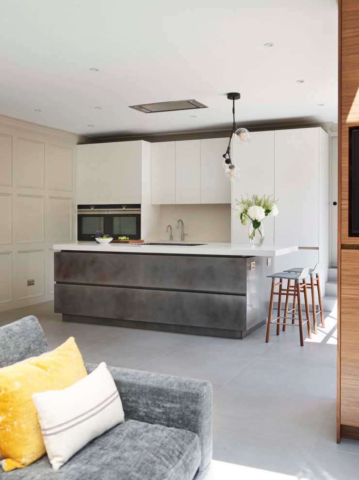 Photo of a large contemporary l-shaped open plan kitchen in London with flat-panel cabinets, white cabinets, panelled appliances, porcelain floors, with island, grey floor and white benchtop.