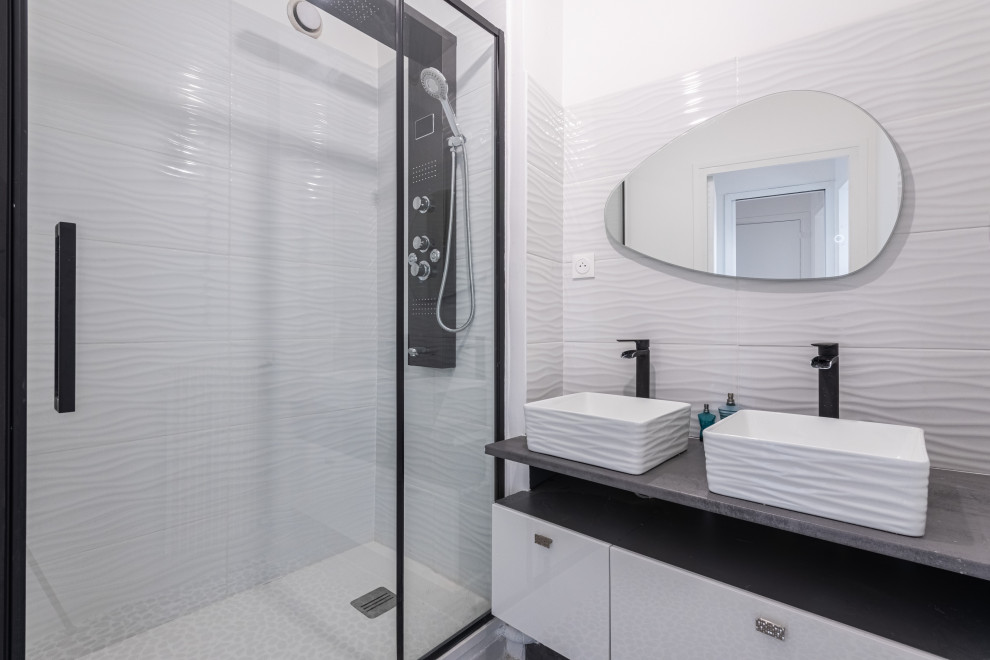 На фото: маленькая серо-белая ванная комната со стиральной машиной в современном стиле с фасадами с декоративным кантом, белыми фасадами, полновстраиваемой ванной, душем в нише, белой плиткой, керамической плиткой, белыми стенами, полом из галечной плитки, душевой кабиной, врезной раковиной, разноцветным полом, душем с распашными дверями, тумбой под две раковины и подвесной тумбой для на участке и в саду с