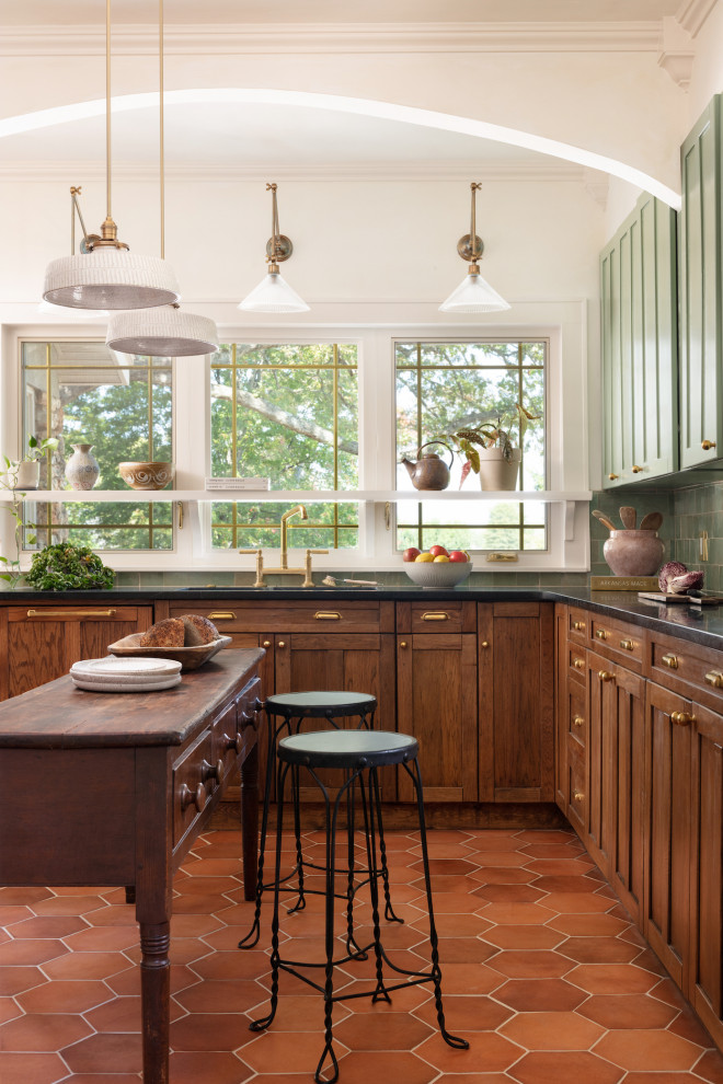 This is an example of a mid-sized transitional u-shaped separate kitchen in Other with an undermount sink, shaker cabinets, medium wood cabinets, soapstone benchtops, green splashback, ceramic splashback, panelled appliances, terra-cotta floors, with island, black benchtop and exposed beam.