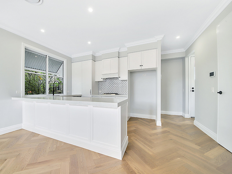 Inspiration for a small traditional u-shaped open plan kitchen in Brisbane with an undermount sink, shaker cabinets, white cabinets, granite benchtops, white splashback, mosaic tile splashback, stainless steel appliances, medium hardwood floors, with island, beige floor and white benchtop.