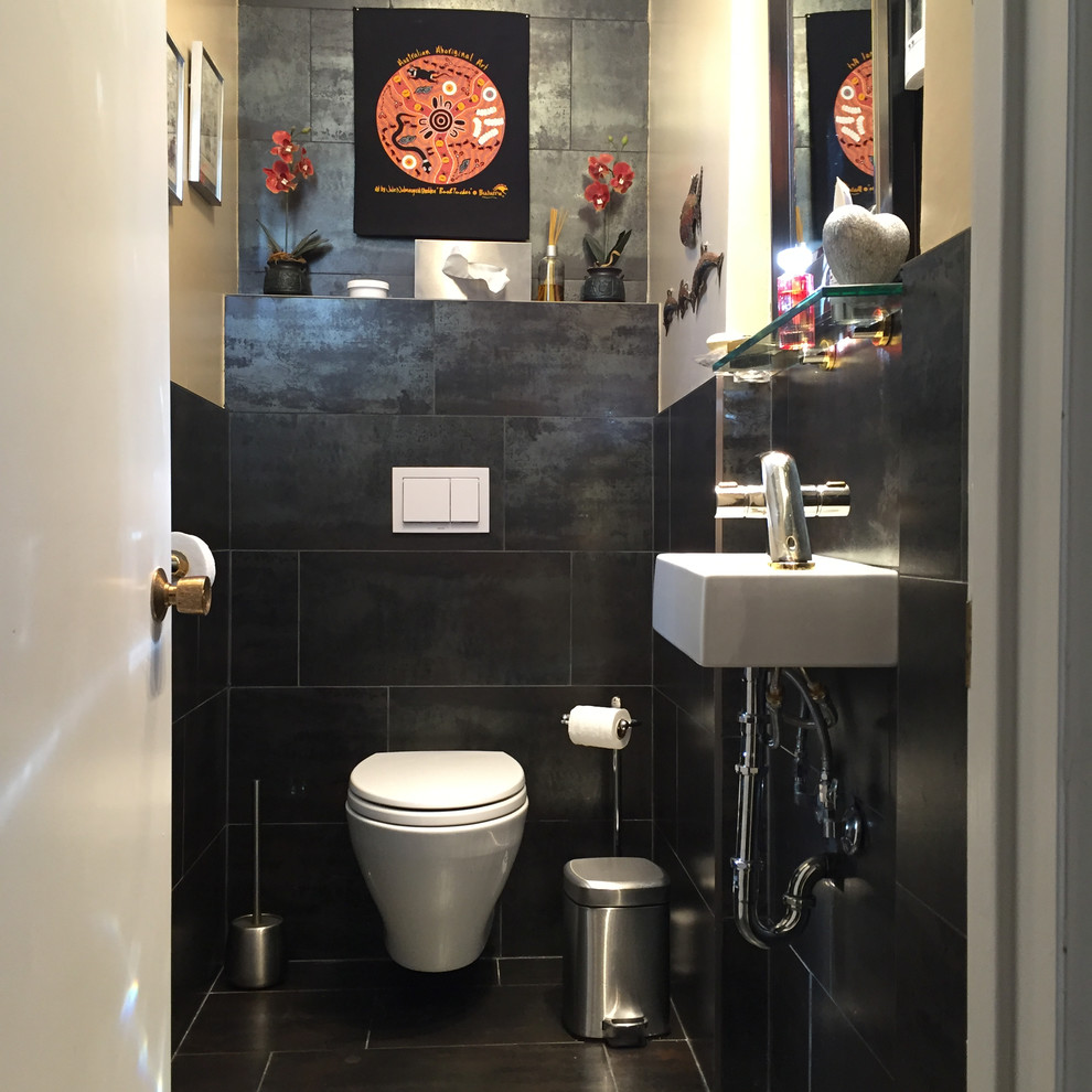 Small modern powder room in Toronto with a wall-mount toilet, black tile, stone tile, slate floors and a wall-mount sink.