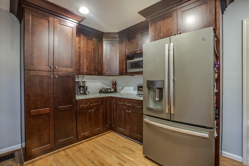 Example of a mid-sized transitional l-shaped light wood floor and yellow floor eat-in kitchen design in Birmingham with a double-bowl sink, shaker cabinets, dark wood cabinets, granite countertops, white backsplash, subway tile backsplash, stainless steel appliances, an island and gray countertops