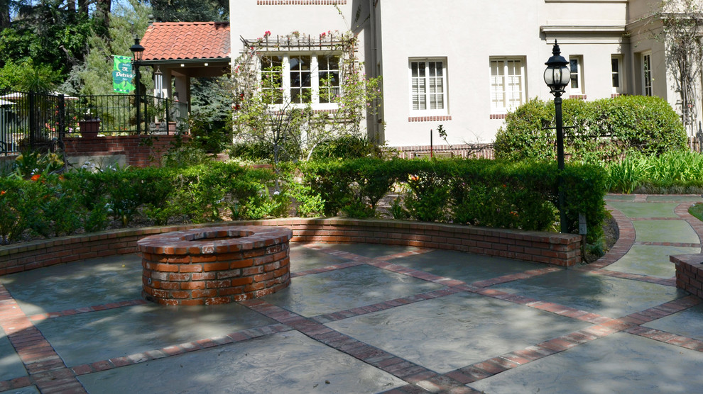 This is an example of a large traditional courtyard patio in Los Angeles with a fire feature, stamped concrete and no cover.