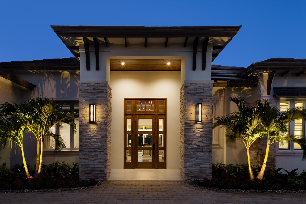 This is an example of an expansive transitional one-storey beige house exterior in Miami with mixed siding.