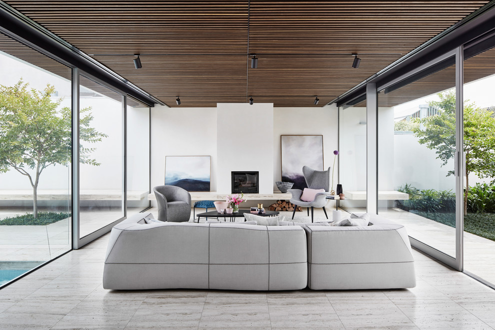 Photo of a modern open concept living room in Melbourne with white walls, a standard fireplace, a plaster fireplace surround and grey floor.