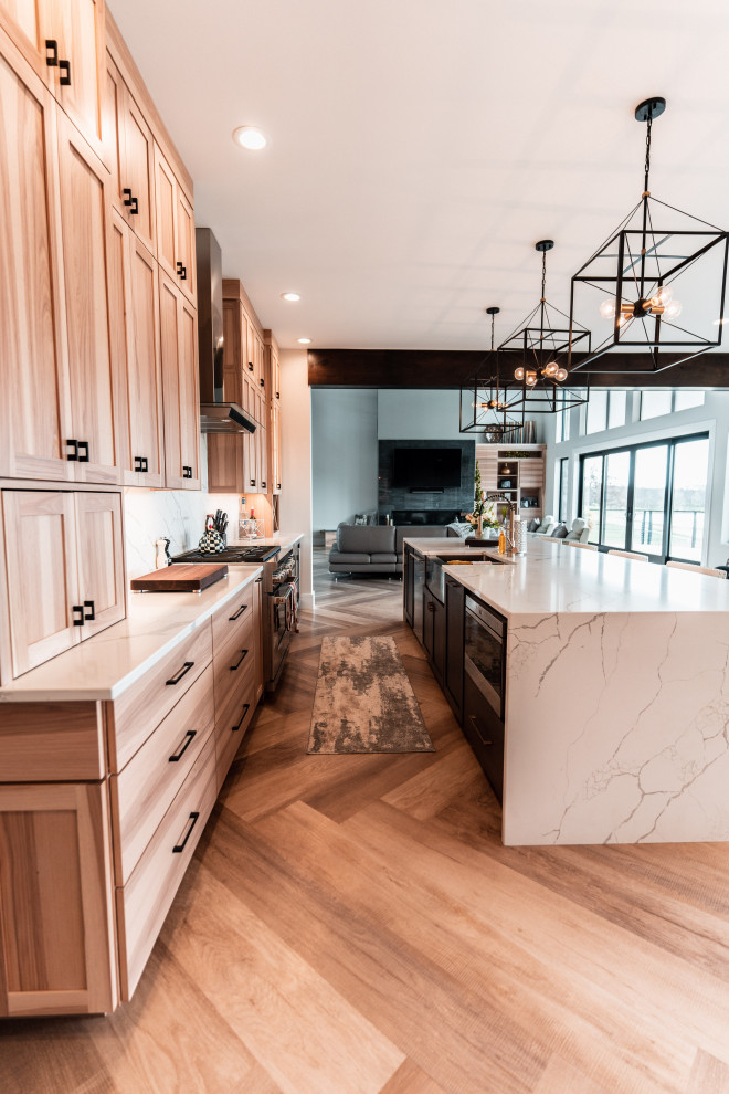 Example of a huge trendy l-shaped light wood floor and exposed beam eat-in kitchen design in Other with a farmhouse sink, shaker cabinets, light wood cabinets, quartz countertops, white backsplash, quartz backsplash, stainless steel appliances, an island and white countertops