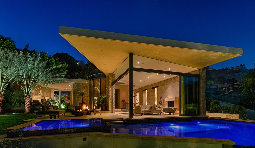 Photo of an expansive contemporary two-storey grey exterior in Los Angeles with stone veneer and a flat roof.