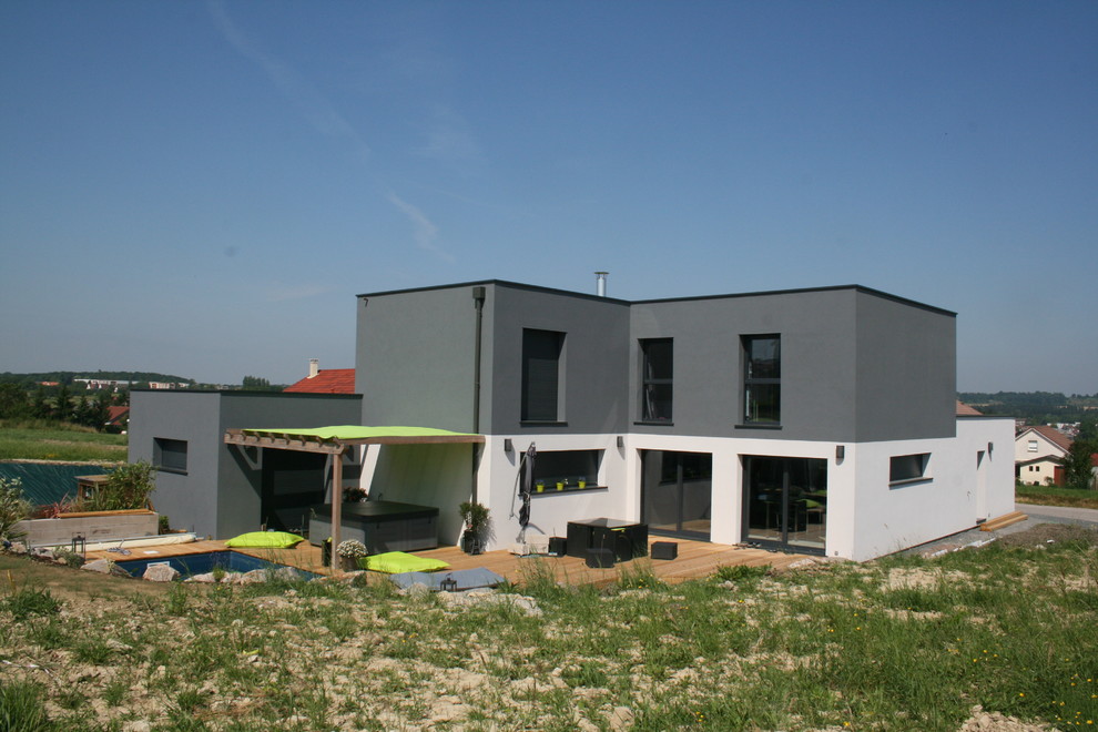Large contemporary two-storey grey house exterior in Nancy with concrete fiberboard siding, a flat roof and a mixed roof.