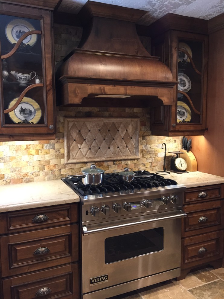 Mid-sized traditional l-shaped eat-in kitchen in Houston with a farmhouse sink, raised-panel cabinets, limestone benchtops, beige splashback, stone tile splashback, panelled appliances, a peninsula, dark wood cabinets and slate floors.