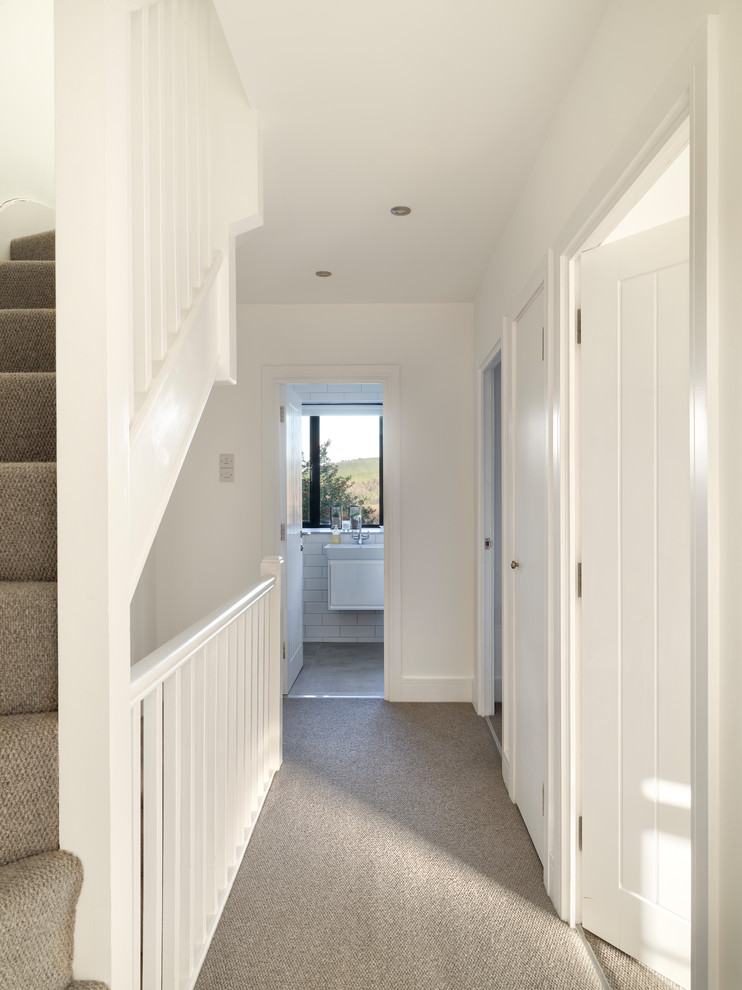 Small contemporary hallway in Sussex with white walls, carpet and grey floor.