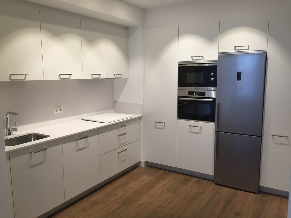 Mid-sized contemporary l-shaped kitchen in Other with a single-bowl sink, flat-panel cabinets, white cabinets, white splashback, medium hardwood floors and no island.