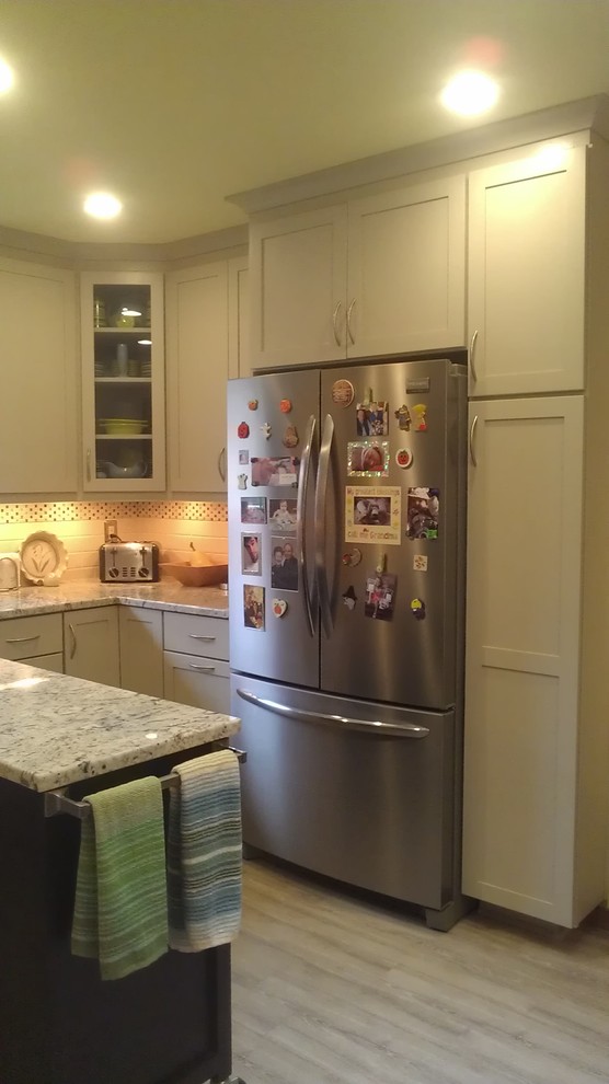 Inspiration for a mid-sized transitional u-shaped vinyl floor home design remodel with an undermount sink, shaker cabinets, white cabinets, granite countertops, white backsplash, subway tile backsplash, stainless steel appliances and an island