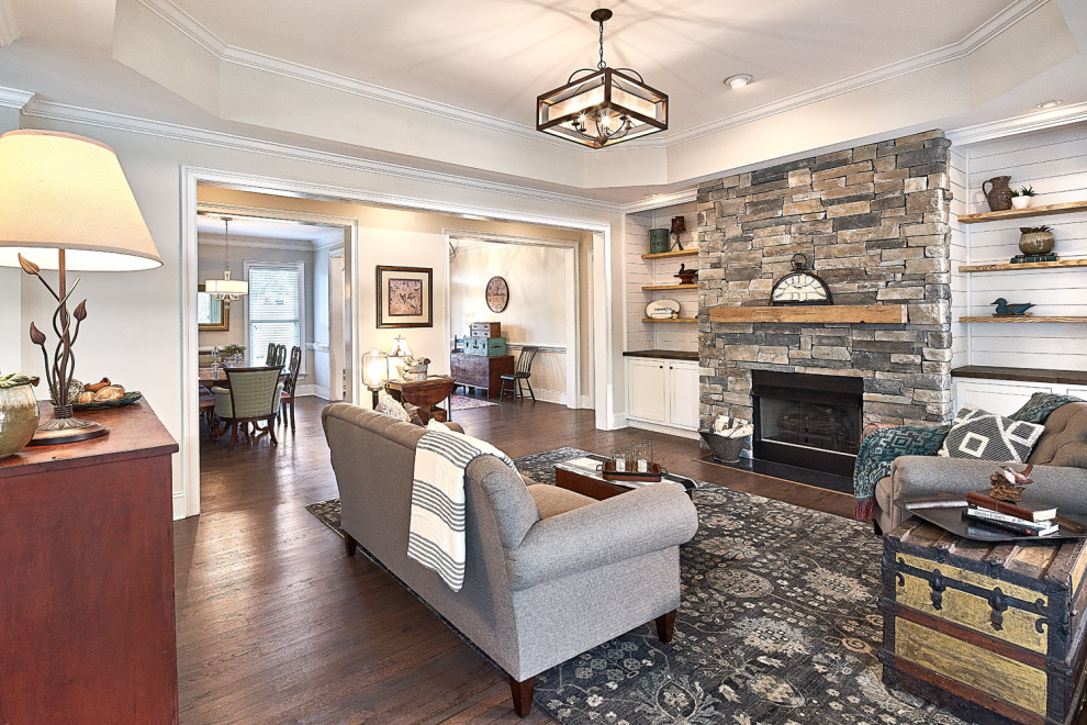 Photo of a mid-sized country open concept family room in Charlotte with beige walls, dark hardwood floors, a standard fireplace, a stone fireplace surround, no tv and brown floor.