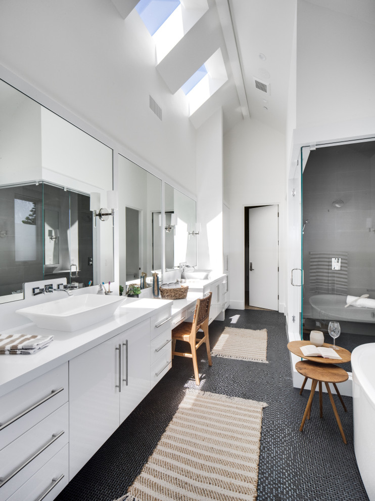 Beach style master bathroom in Orange County with flat-panel cabinets, white cabinets, a freestanding tub, a corner shower, white walls, a vessel sink, black floor, white benchtops, a double vanity, a floating vanity and vaulted.