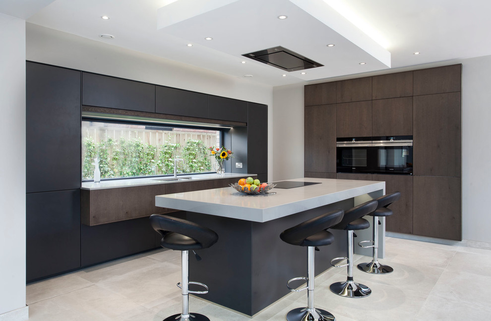 Mid-sized contemporary l-shaped eat-in kitchen in Belfast with a double-bowl sink, flat-panel cabinets, black cabinets, quartzite benchtops, black appliances, with island, white floor and white benchtop.