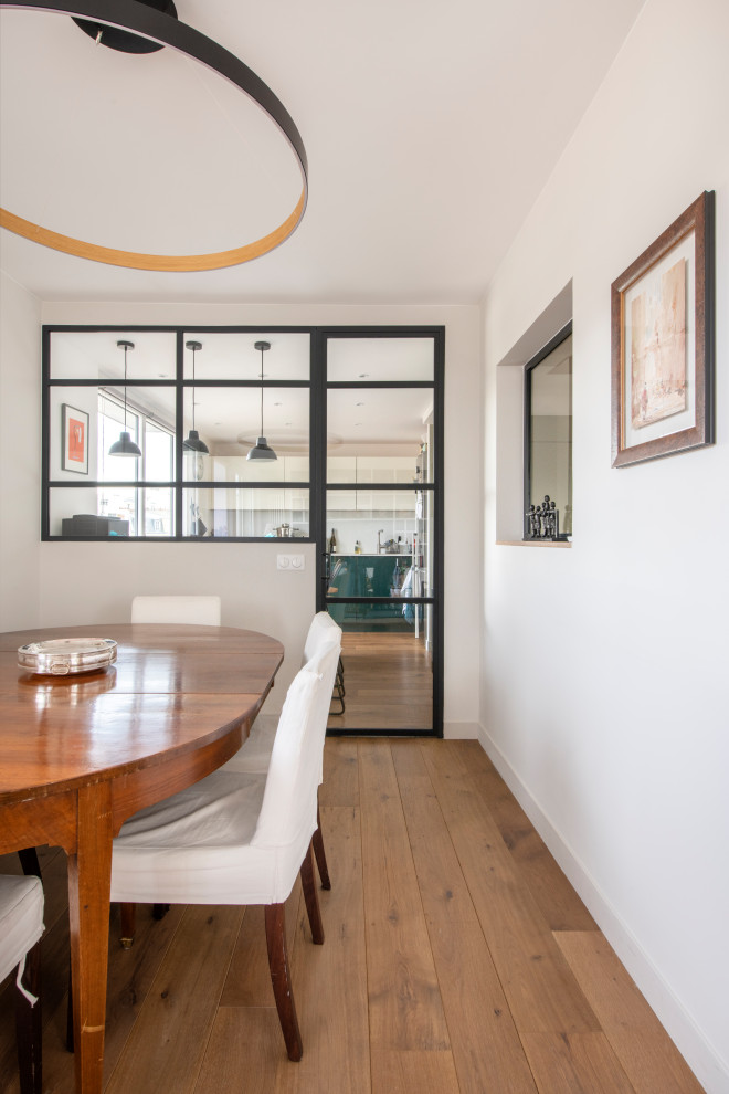 Inspiration pour une salle à manger minimaliste fermée et de taille moyenne avec un mur blanc, un sol en bois brun, aucune cheminée et un sol marron.