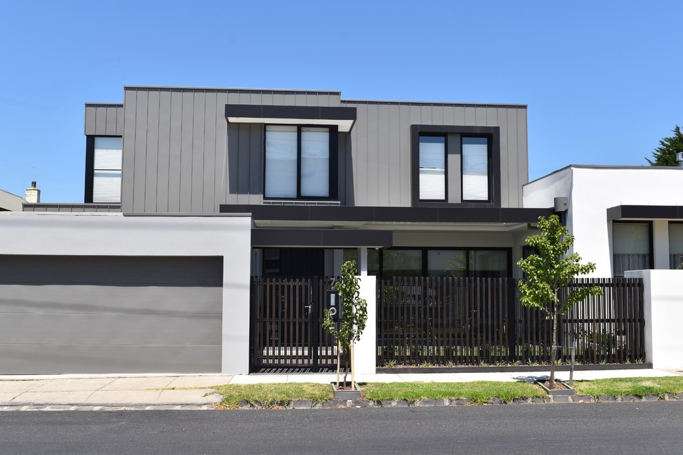 Photo of a mid-sized contemporary two-storey grey townhouse exterior in Melbourne with metal siding, a flat roof and a metal roof.
