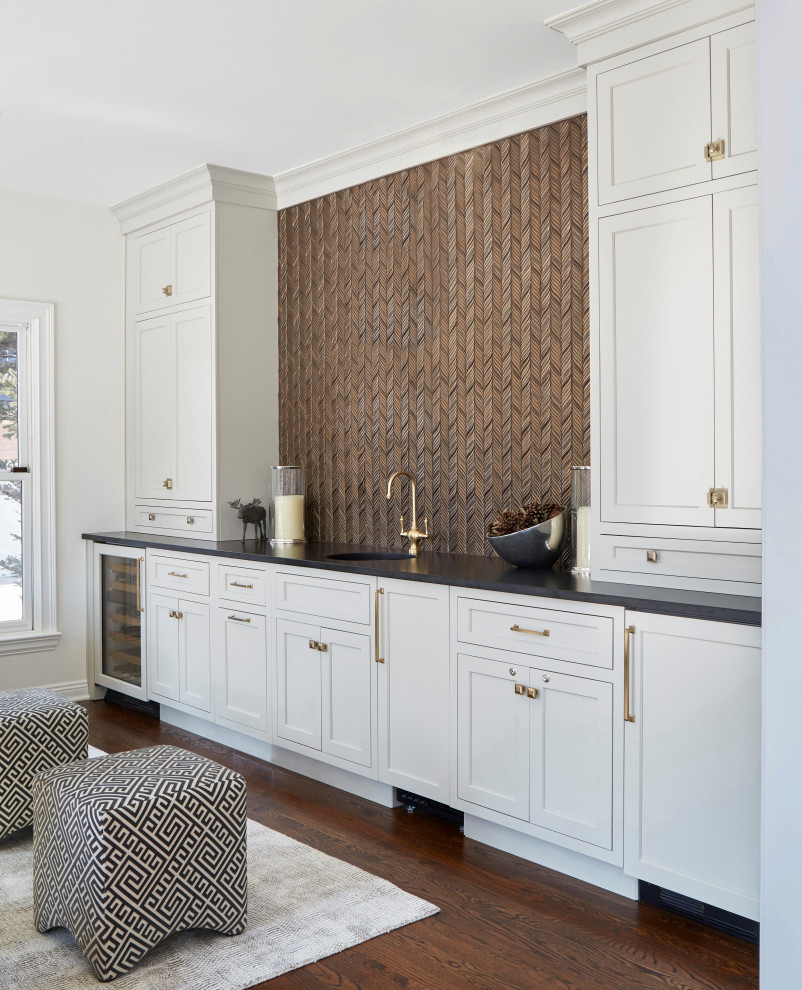 Example of a large transitional single-wall medium tone wood floor and brown floor wet bar design in Chicago with an undermount sink, recessed-panel cabinets, gray cabinets, quartz countertops, brown backsplash, mosaic tile backsplash and black countertops
