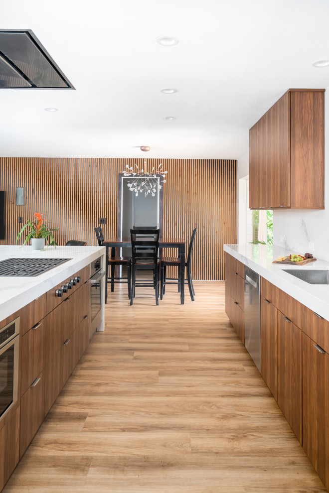 Exempel på ett mellanstort modernt vit vitt kök, med en undermonterad diskho, släta luckor, skåp i mellenmörkt trä, bänkskiva i kvarts, vitt stänkskydd, rostfria vitvaror, vinylgolv, en köksö och brunt golv