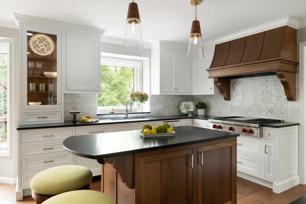 Example of a mid-sized classic u-shaped medium tone wood floor open concept kitchen design in Minneapolis with an undermount sink, white cabinets, quartz countertops, multicolored backsplash, cement tile backsplash, stainless steel appliances, an island and black countertops