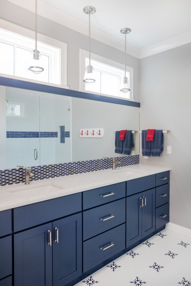 This is an example of a large nautical ensuite bathroom in Milwaukee with flat-panel cabinets, blue cabinets, an alcove shower, grey walls, porcelain flooring, a submerged sink, engineered stone worktops, white floors, a hinged door, white worktops, an enclosed toilet, double sinks and a built in vanity unit.