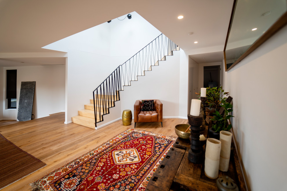 Expansive asian foyer in Sydney with light hardwood floors and brown floor.