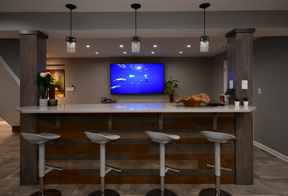 Basement - large transitional porcelain tile and gray floor basement idea in DC Metro with a bar, gray walls, a standard fireplace and a brick fireplace