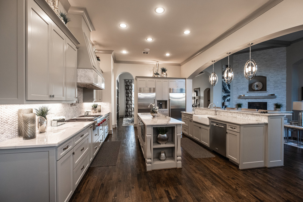 Transitional l-shaped eat-in kitchen in Dallas with a farmhouse sink, flat-panel cabinets, grey cabinets, marble benchtops, white splashback, marble splashback, stainless steel appliances, dark hardwood floors, with island, brown floor and white benchtop.