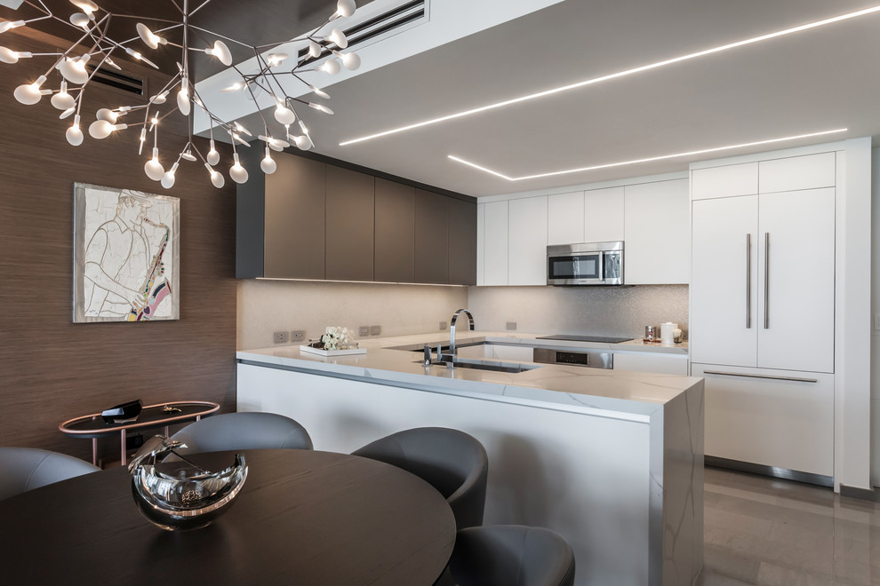 Design ideas for a contemporary u-shaped kitchen in Miami with an undermount sink, flat-panel cabinets, white cabinets, panelled appliances, a peninsula, grey floor and white benchtop.