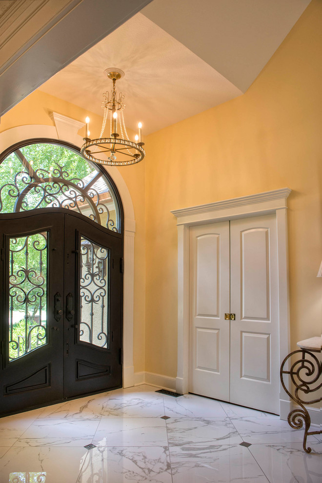 Design ideas for a large mediterranean foyer in Kansas City with yellow walls, porcelain floors, a double front door, white floor and a black front door.