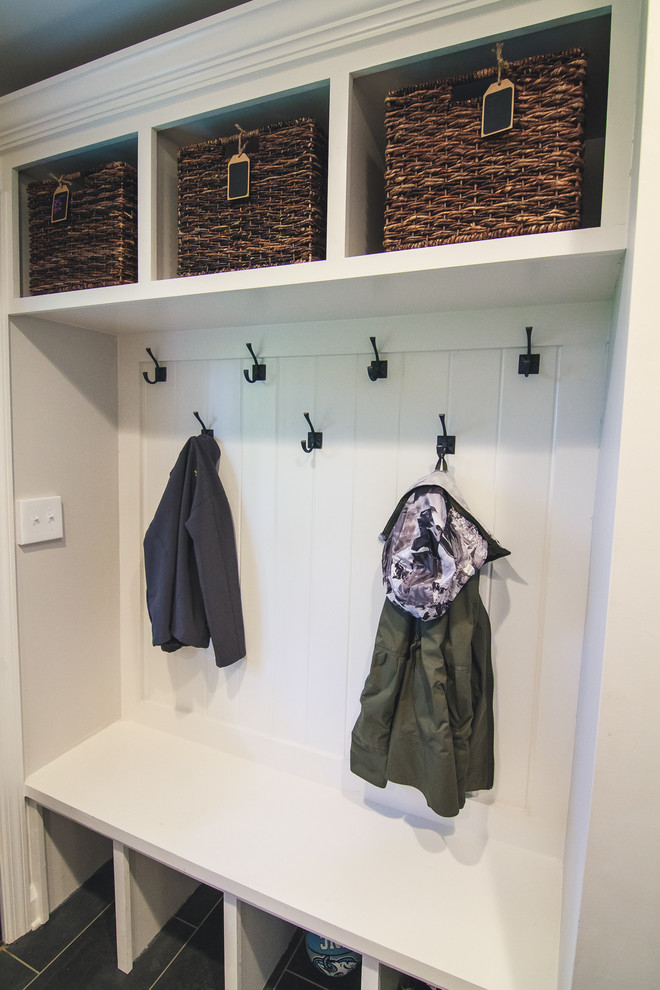 This is an example of a small traditional mudroom in Baltimore with white walls, ceramic floors and black floor.