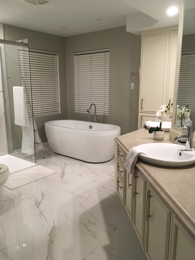 Photo of a mid-sized modern master bathroom in Montreal with furniture-like cabinets, beige cabinets, a freestanding tub, a corner shower, a two-piece toilet, white tile, porcelain tile, grey walls, porcelain floors, a vessel sink, laminate benchtops, white floor, a sliding shower screen and brown benchtops.