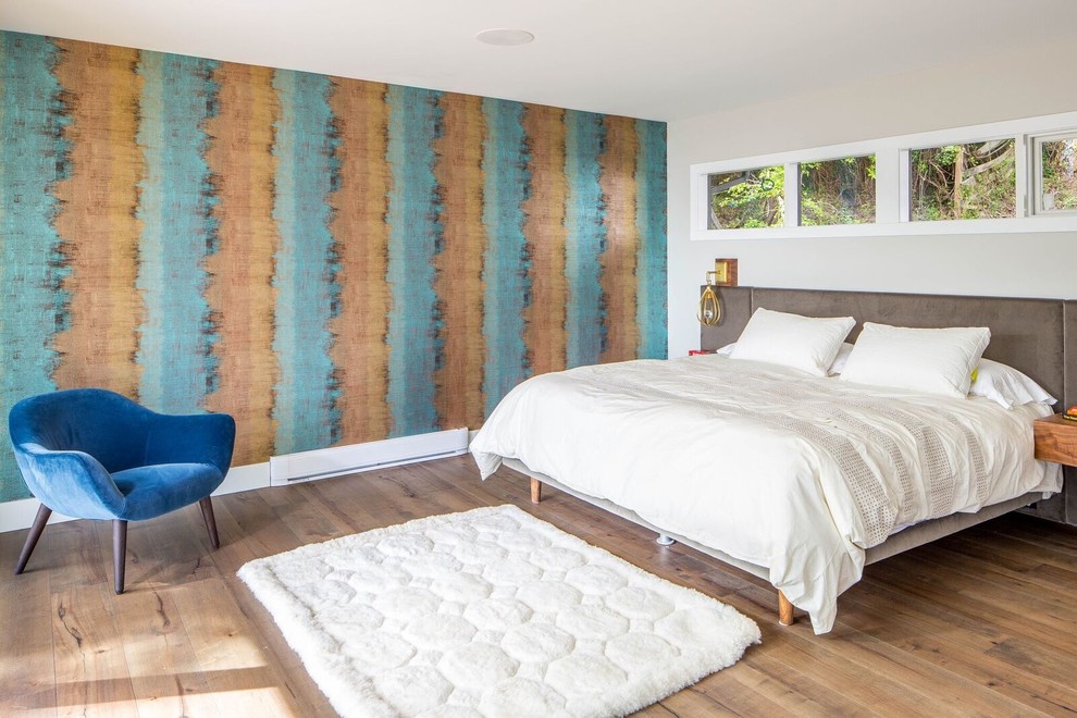 This is an example of a beach style master bedroom in Vancouver with multi-coloured walls, medium hardwood floors and no fireplace.