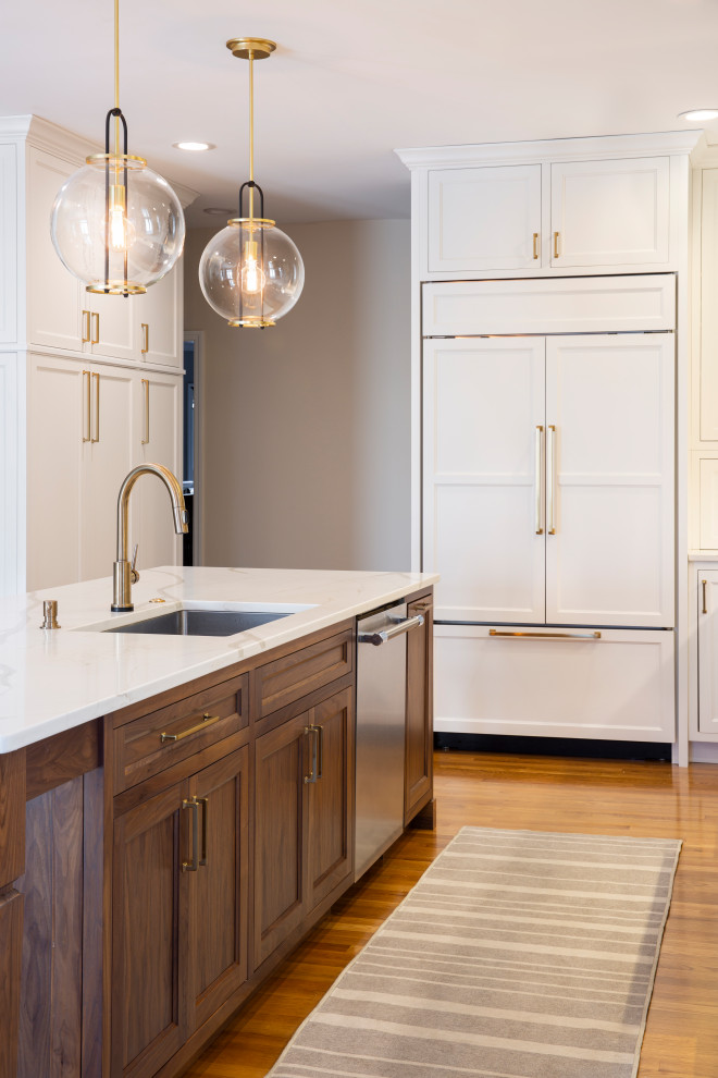 Inspiration for a mid-sized traditional l-shaped eat-in kitchen in Cincinnati with an undermount sink, medium wood cabinets, quartz benchtops, beige splashback, marble splashback, medium hardwood floors, with island, white benchtop and panelled appliances.