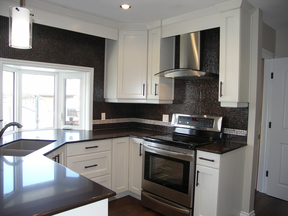 Inspiration for a transitional u-shaped medium tone wood floor kitchen remodel in Edmonton with an undermount sink, shaker cabinets, white cabinets, granite countertops, black backsplash and stainless steel appliances