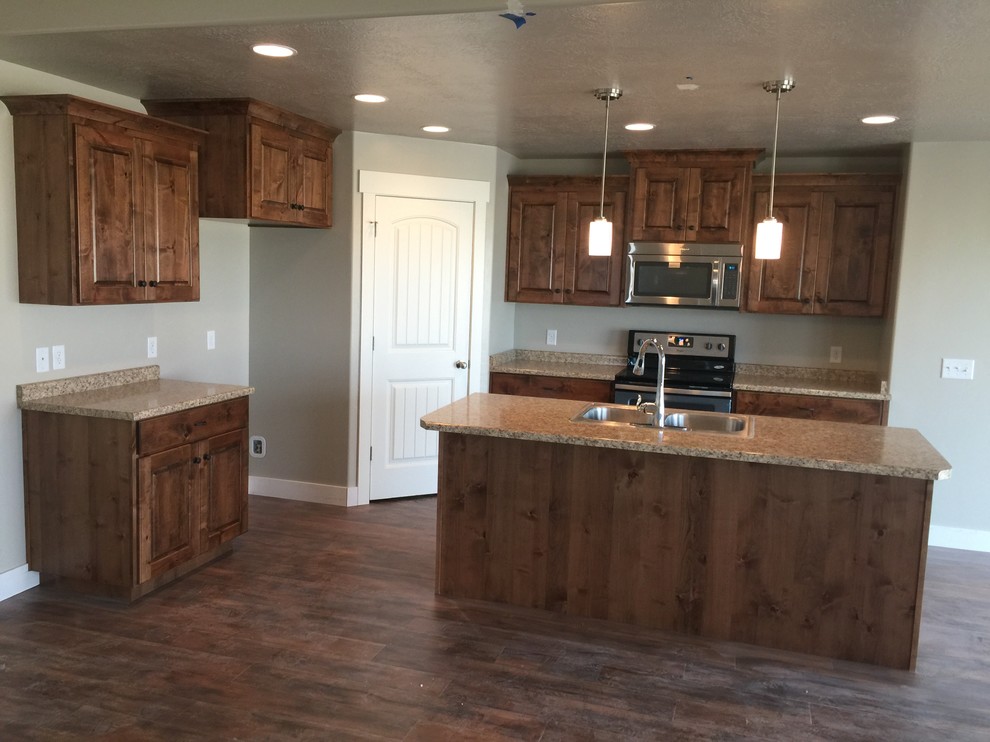 Traditional l-shaped kitchen in Salt Lake City with a drop-in sink, raised-panel cabinets, medium wood cabinets and with island.