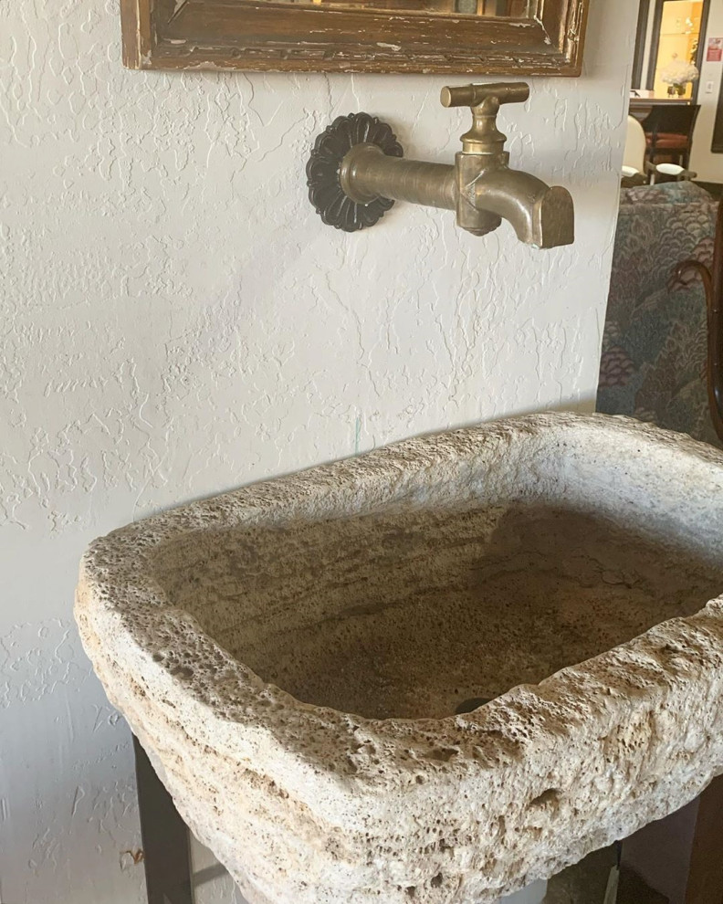 Foto på ett lantligt badrum, med kalkstensgolv, ett avlångt handfat och bänkskiva i kalksten