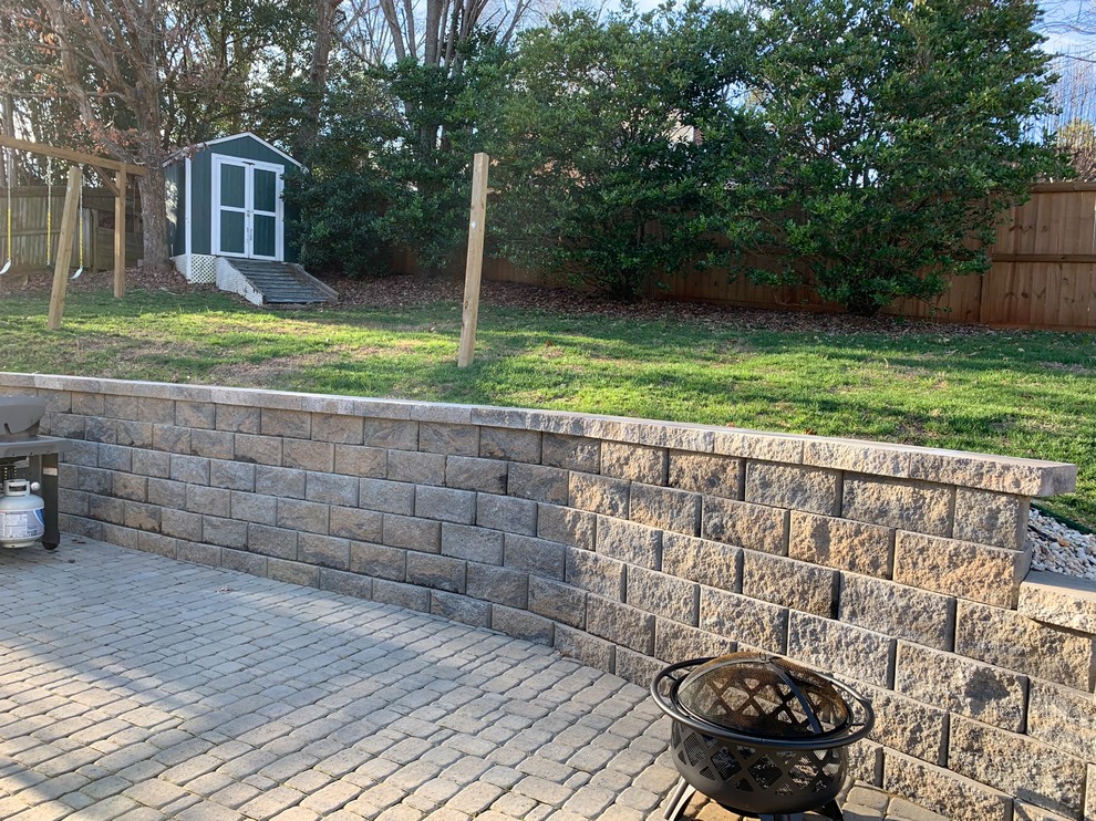 This is an example of a mid-sized traditional backyard full sun garden in Charlotte with a retaining wall and natural stone pavers.