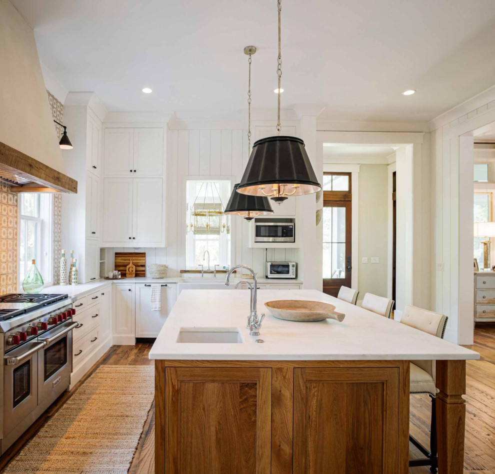 Country u-shaped kitchen in Other with a farmhouse sink, shaker cabinets, white cabinets, marble benchtops, ceramic splashback, stainless steel appliances, medium hardwood floors, with island, brown floor and white benchtop.
