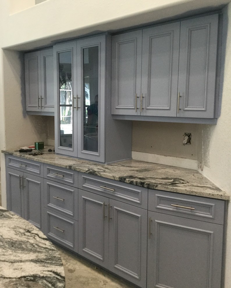 Inspiration for a mid-sized contemporary galley eat-in kitchen in Miami with an undermount sink, flat-panel cabinets, blue cabinets, granite benchtops, white splashback, stone tile splashback, stainless steel appliances, ceramic floors and with island.