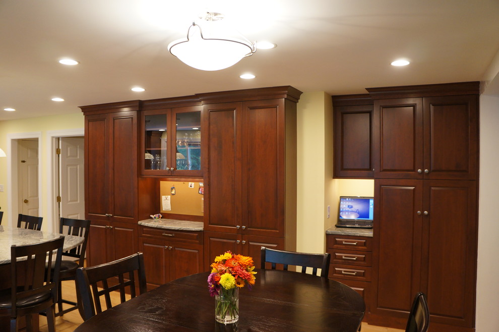 Example of a mid-sized transitional galley light wood floor eat-in kitchen design in Boston with an undermount sink, raised-panel cabinets, dark wood cabinets, quartz countertops, white backsplash, ceramic backsplash, stainless steel appliances and an island