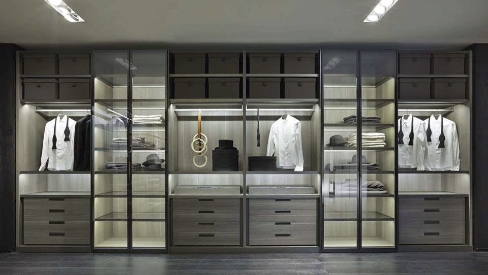 Inspiration for a large modern men's storage and wardrobe in Salt Lake City with glass-front cabinets, dark wood cabinets and dark hardwood floors.
