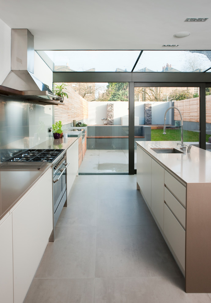 Large contemporary galley eat-in kitchen in London with flat-panel cabinets, white cabinets, with island, grey floor, solid surface benchtops and brown benchtop.
