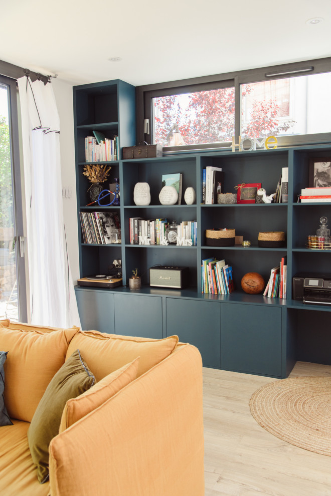 Modelo de sala de estar con biblioteca abierta clásica renovada de tamaño medio con paredes blancas, suelo de madera clara, estufa de leña, marco de chimenea de baldosas y/o azulejos y televisor independiente