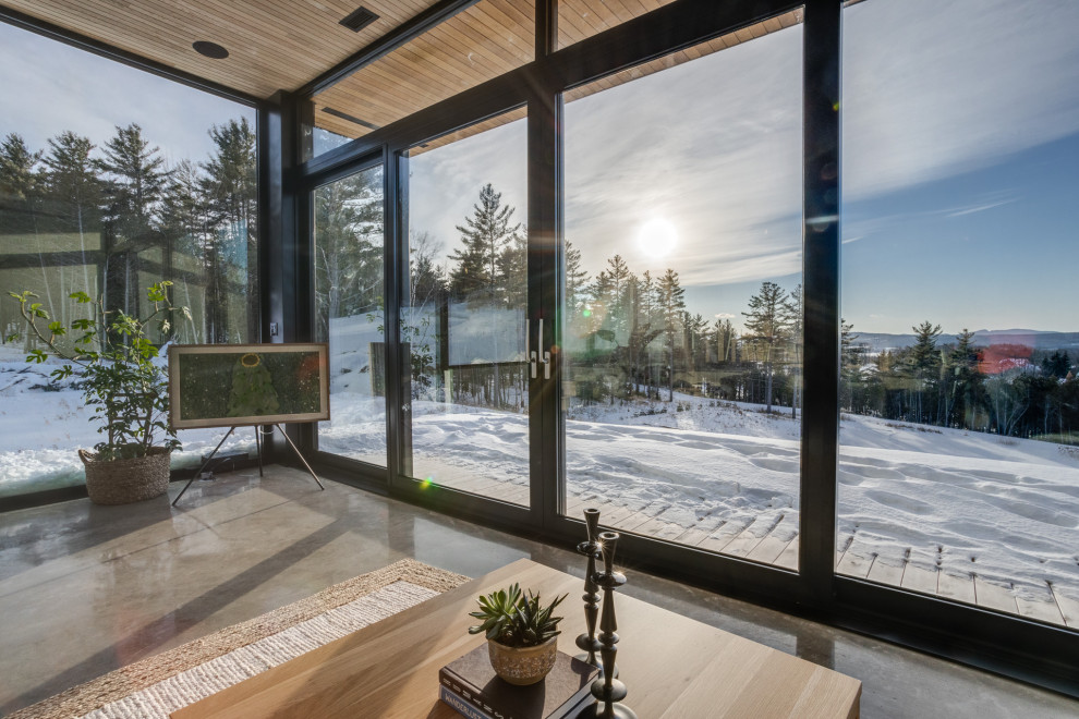 Imagen de salón abierto escandinavo con suelo de cemento, chimenea de esquina, marco de chimenea de baldosas y/o azulejos, suelo gris y madera
