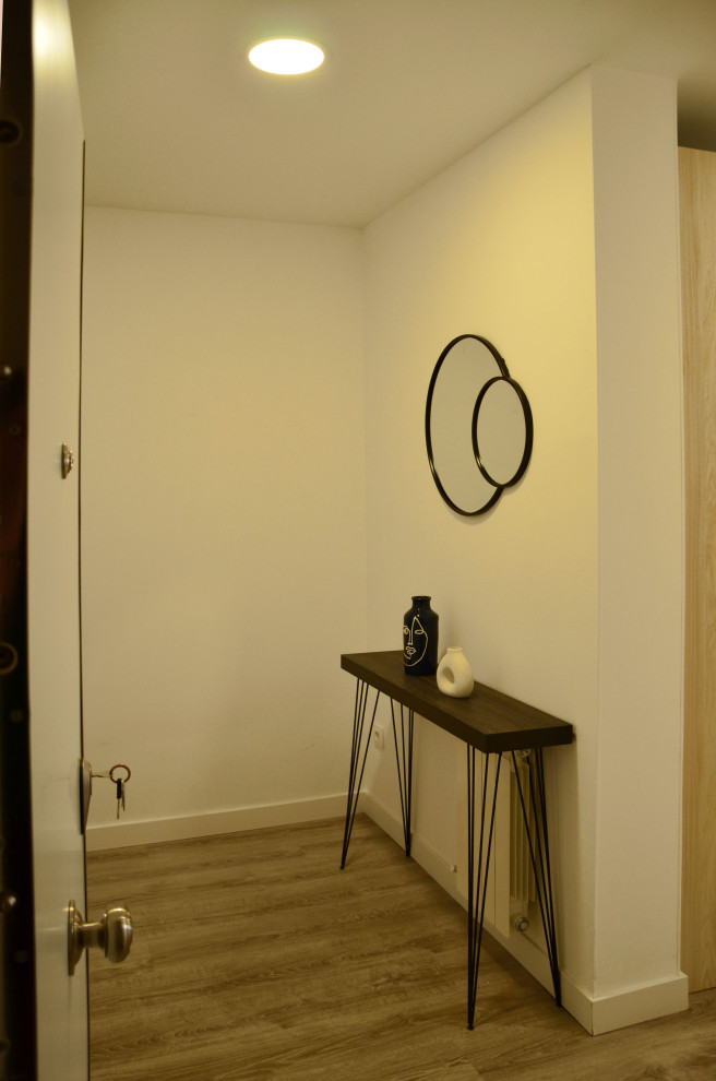 This is an example of a large transitional vestibule in Madrid with white walls, laminate floors and a single front door.