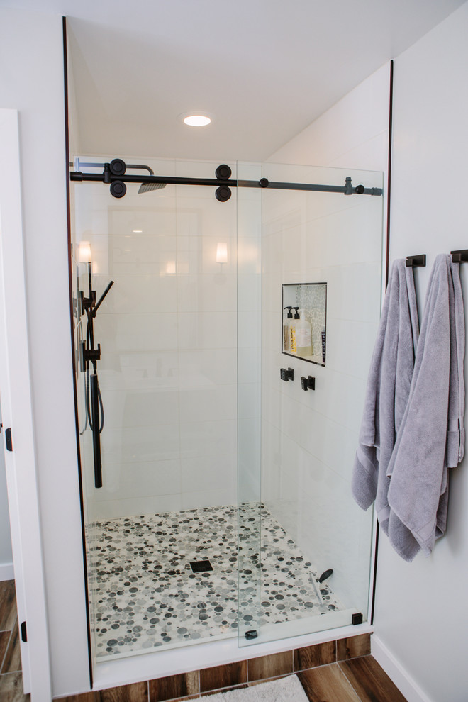 This is an example of a mid-sized country master bathroom in Denver with furniture-like cabinets, distressed cabinets, a freestanding tub, an alcove shower, a one-piece toilet, white tile, ceramic tile, grey walls, porcelain floors, an undermount sink, engineered quartz benchtops, brown floor and a sliding shower screen.
