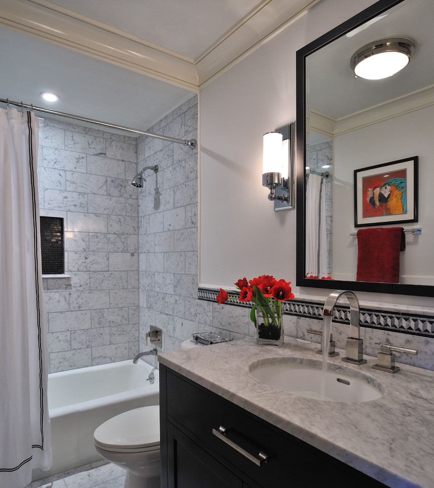 This is an example of a mid-sized contemporary 3/4 bathroom in Houston with recessed-panel cabinets, black cabinets, an alcove tub, a shower/bathtub combo, a two-piece toilet, gray tile, multi-coloured tile, white tile, stone tile, white walls, marble floors, an undermount sink and marble benchtops.