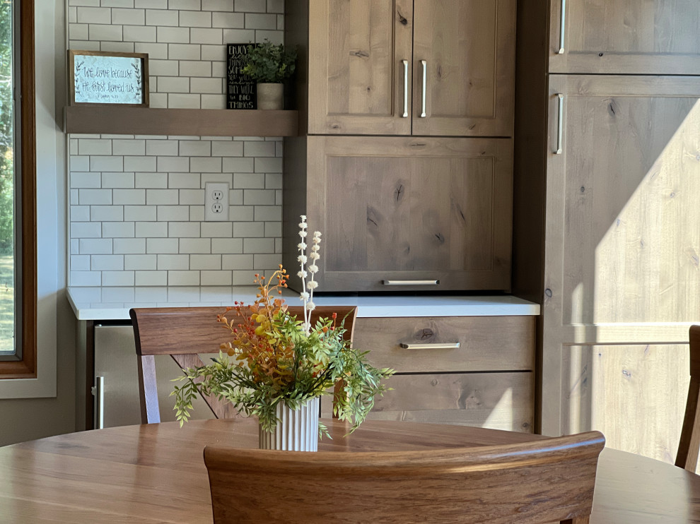Cette photo montre une salle à manger ouverte sur la cuisine chic de taille moyenne avec un mur gris, parquet clair, un sol marron et poutres apparentes.