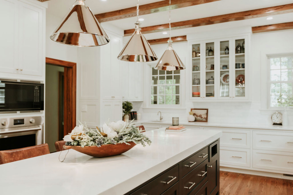 Eat-in kitchen - large transitional u-shaped medium tone wood floor, brown floor and exposed beam eat-in kitchen idea with a single-bowl sink, recessed-panel cabinets, white cabinets, quartz countertops, white backsplash, marble backsplash, stainless steel appliances, an island and white countertops
